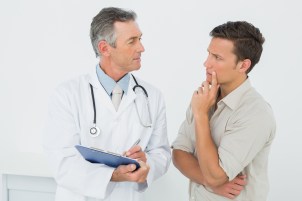 Male doctor discussing reports with patient in medical office